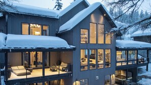 A large, modern two-story building with multiple balconies and large windows, surrounded by snow.