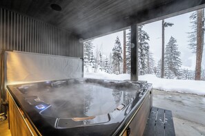 Un jacuzzi con vistas a árboles nevados.