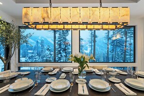 Mesa de comedor para seis personas con una amplia ventana que da a un bosque nevado.