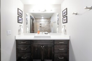 Une salle de bain avec un grand miroir, deux lavabos et une douche.