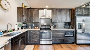A modern kitchen with dark wood cabinets, stainless steel appliances, and a built-in oven. - Located in Heart Downtown Whitefish, Walking Distance to River + Short Drive to Skiing! (Whitefish)