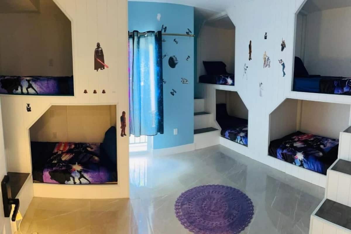 Quarto com beliches, parede azul e tapete roxo.