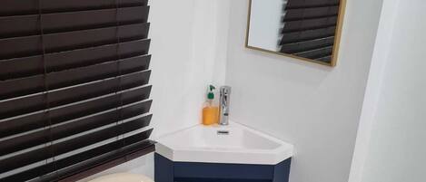 Un baño con lavamanos blanco, espejo y retrete.