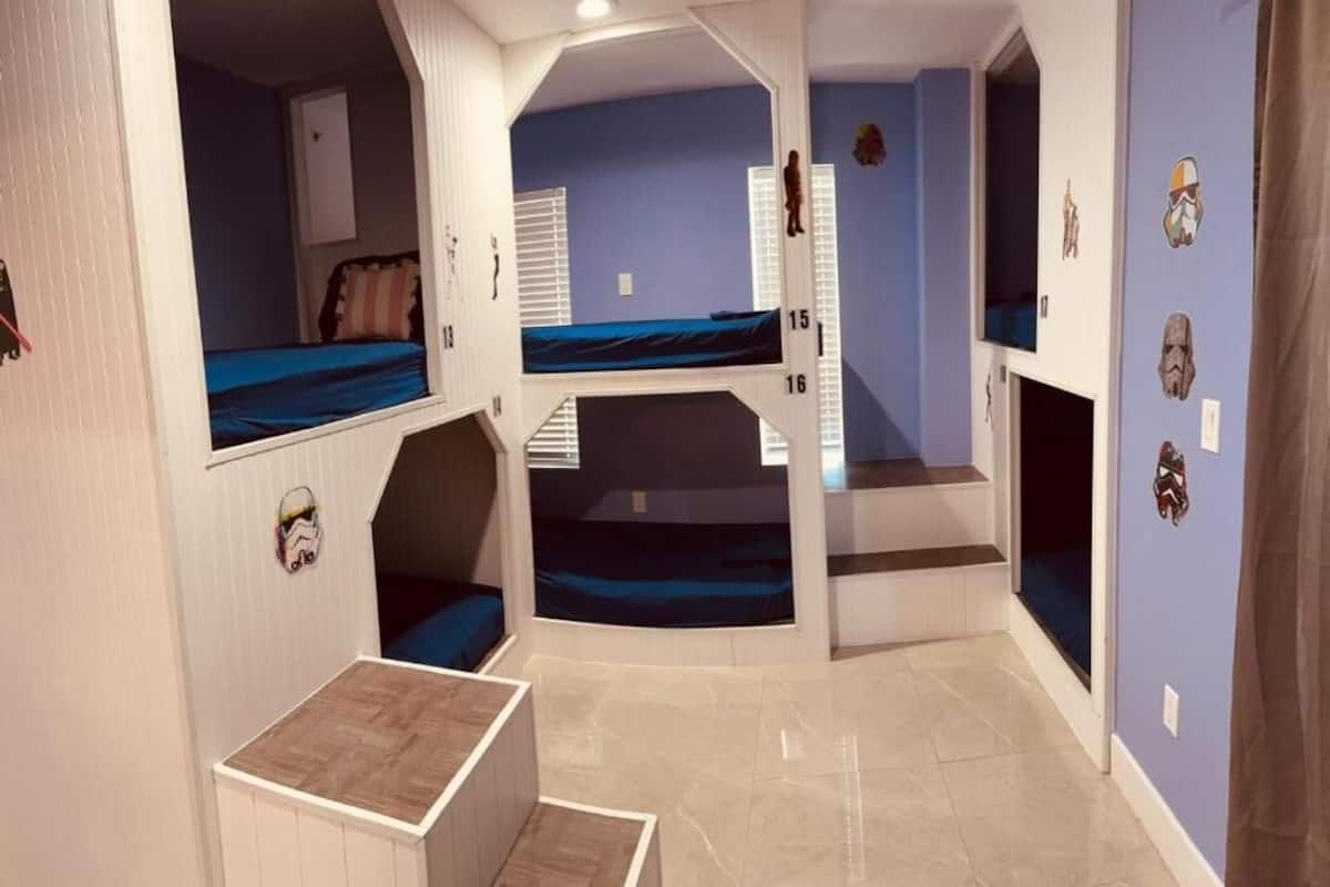 Quarto com beliches, um pequeno espaço de estar e decorações nas paredes inspiradas em Star Wars.