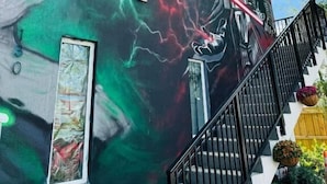 A building with a mural featuring a figure with a red lightsaber, a green and red circular symbol, and lightning effects. - Atrium Design District (Miami)