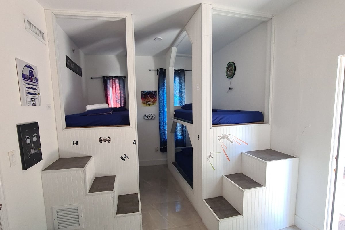 Quarto com beliches, uma janela pequena e um pôster de Star Wars.