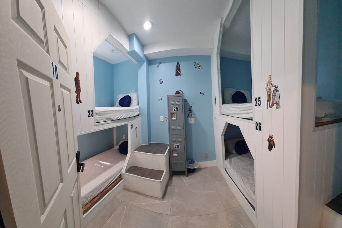 Quarto com beliches, um guarda-roupa e uma pequena escrivaninha.