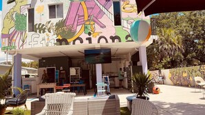 An outdoor seating area with wicker furniture and a colorful mural on the building. - Atrium Design District (Miami)