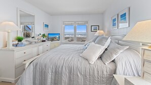 Un dormitorio con cama, mesitas de noche, cómoda, ventana con vistas y espejo.