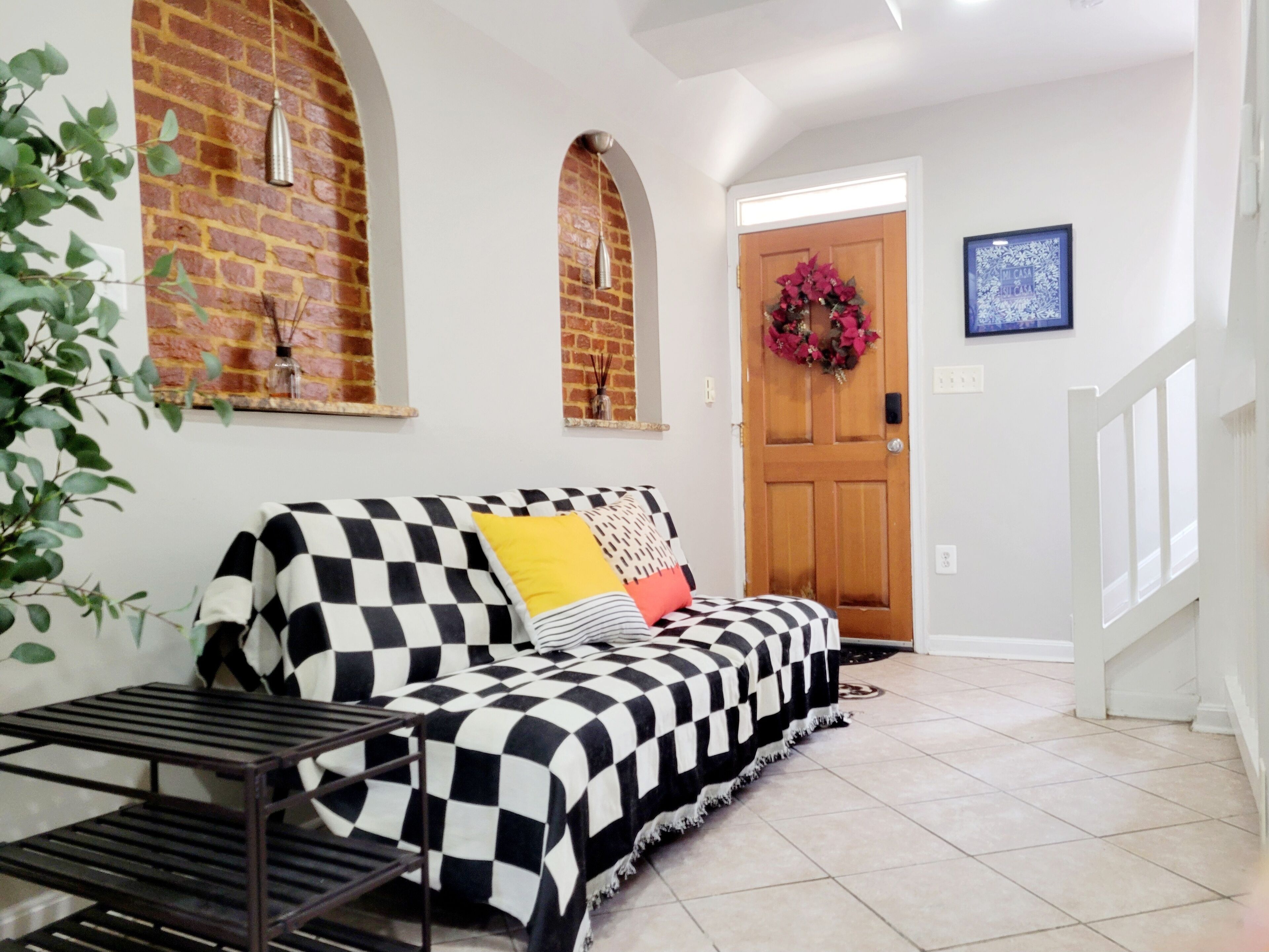 A living room with a checkered sofa, a small table, and a door with a wreath.