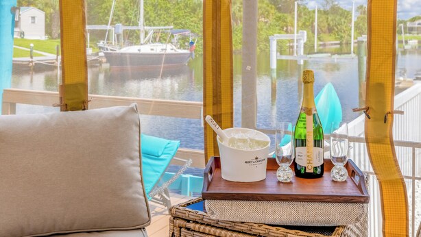 A view from a boat deck with a table holding a bottle of champagne, a bucket of ice, and glasses.