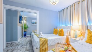 A hotel room with a bed, bedside table, lamp, and a tray with snacks.