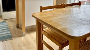 Une cuisine avec des meubles de rangement en bois, un four à micro-ondes et un réfrigérateur. On y trouve une table à manger avec des chaises, et un panier posé sur le comptoir.