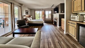 Ein geräumiges Zimmer mit einem Bett, einer Couch, einem Esstisch und einer Küchenzeile inklusive Schränken und einer Mikrowelle.