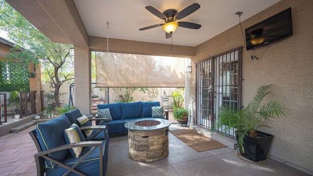An outdoor patio with a stone fire pit, blue sofa, and metal chairs.