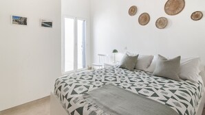Un dormitorio con cama, una silla, un escritorio y una ventana.