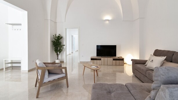 Una sala de estar moderna con un televisor de pantalla plana, un sofá, una mesa de centro y una silla.