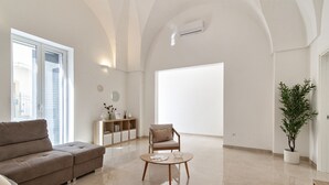 Un salón amplio con un gran ventanal, un sofá, una mesa de centro de madera y una planta en maceta.