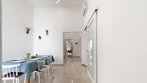 Un comedor moderno con una larga mesa dispuesta para una comida, sillas blancas y un diseño limpio y minimalista.