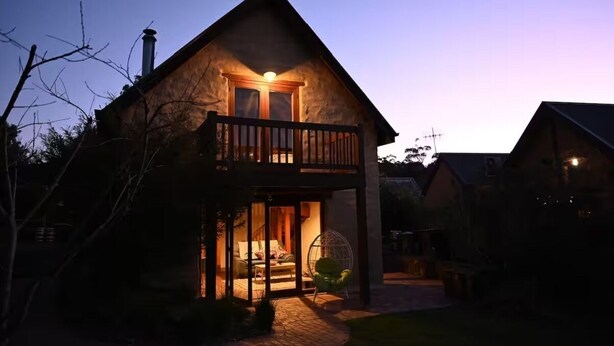 A two-story house with a balcony, a chimney, and a well-lit entrance. - Sue's House (Saint Andrews)