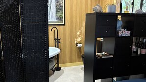 A bedroom with a bed, a black wardrobe, a sink, and a framed picture of a waterfall.