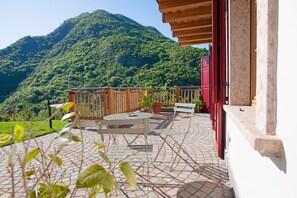A patio with a table and chairs, a wooden fence, and a mountain view.