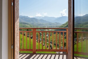 A balcony with a view of green hills and mountains.