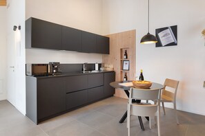 A modern kitchen with dark cabinets, a round dining table, and a pendant light.