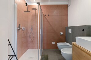 A modern bathroom with a glass-enclosed shower, a white toilet, and a wooden vanity.