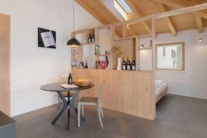A modern interior with a dining area, wooden beams, a bed, and wine bottles. - Studio 'Maso Cantanghel' with Mountain View, Wi-Fi and Air Conditioning (Civezzano)