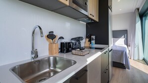 Eine moderne Küchenzeile mit Spüle aus Edelstahl, einer Kaffeemaschine und einer Mikrowelle.