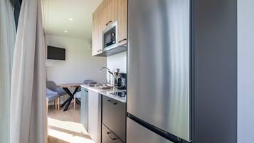 Cozinha moderna com geladeira de aço inoxidável, micro-ondas e cafeteira na bancada.