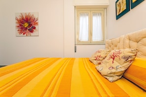 Ein Bett mit gestreifter Bettwäsche, ein Fenster mit Vorhängen und ein Wandbild.