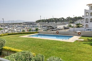 Un port de plaisance avec des bateaux, une piscine et un bâtiment doté de balcons.