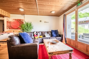 Una habitación acogedora con un sofá de cuero, una mesa de centro de madera y un ventanal con vistas a zonas verdes.