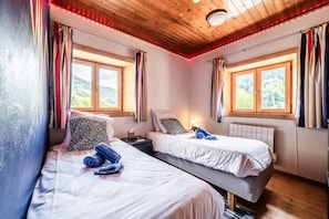 Una habitación con dos camas, una mesita de noche, una lámpara y una ventana con cortinas.
