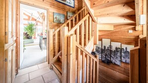 A wooden interior with a staircase, wooden walls, and a door leading outside.