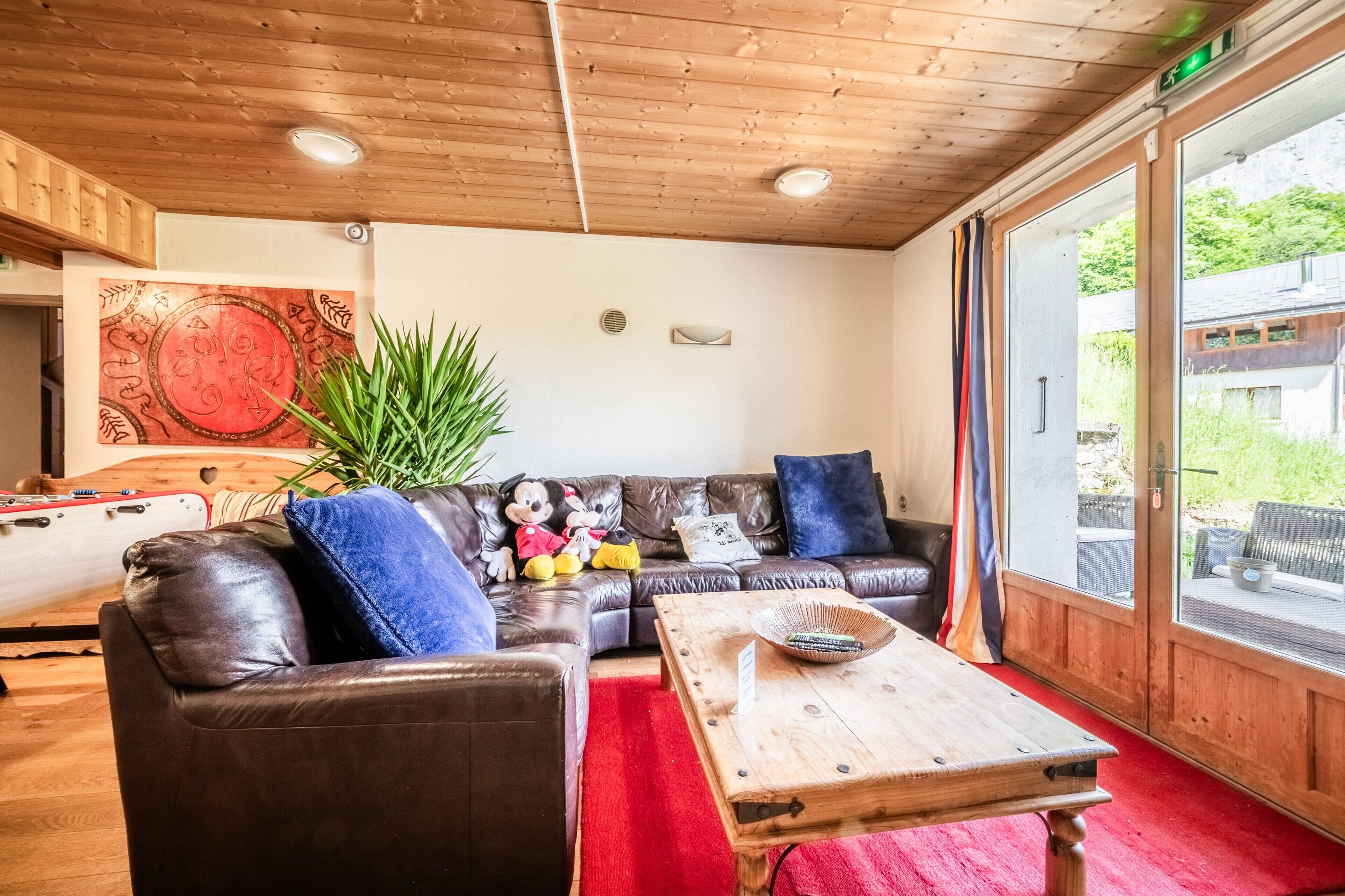 Une pièce chaleureuse avec un canapé en cuir, une table basse en bois et une grande fenêtre donnant sur un paysage verdoyant.