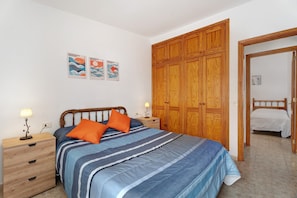 A bedroom with a bed, wooden wardrobe, nightstands, and wall art. - Vacation 'The House Of Abades' with Wi-Fi (Abades)