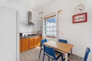 A kitchen with wooden cabinets, a stove, a microwave, and a dining table with blue chairs. - Vacation 'The House Of Abades' with Wi-Fi (Abades)