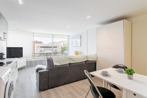 A modern apartment with a dining area, sofa, and kitchen.