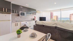 A modern kitchen with grey cabinets, a built-in microwave, and a large window with a view of the city. - Apartment 'Vistas Al Mar' with Shared Pool, Wi-Fi and Air Conditioning (Alicante (Alacant))