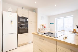 A modern kitchen with a refrigerator, oven, microwave, and wooden cabinets.