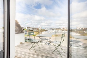 A balcony with a table and chairs, overlooking a marina with boats and buildings.