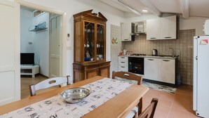A kitchen with a dining table, cabinets, and a microwave.