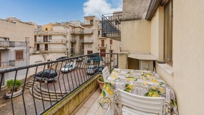 A balcony with a table, chairs, and potted plants.