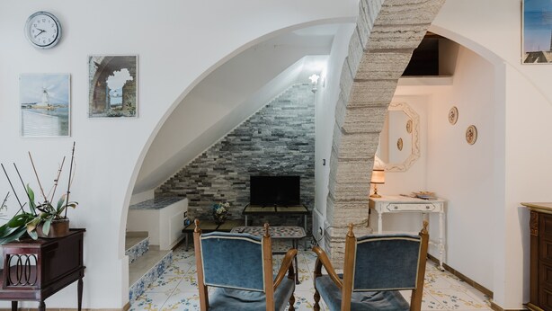 Una sala de estar con chimenea de piedra, dos sillones azules, un televisor y un reloj en la pared.