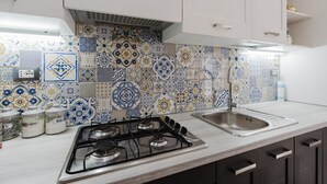 Una cocina con estufa a gas, un lavamanos y azulejos decorativos.
