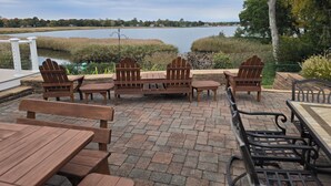 Une terrasse dotée de chaises et de tables Adirondack en bois, donnant sur un lac.