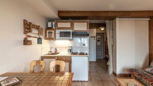 A compact kitchen with wooden cabinets, a microwave, and a coffee maker. There is a dining table with chairs and a patterned table runner.